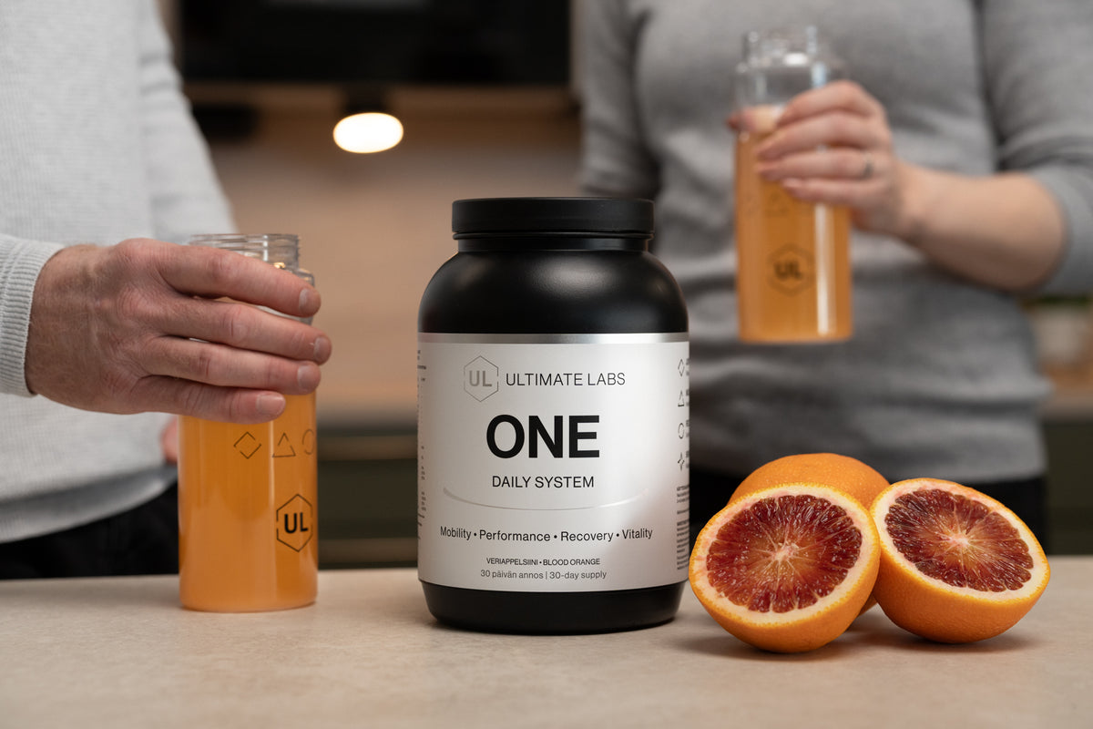 Ultimate Labs ONE Daily System -ravintolisäpurkki, veriappelsiinit ja kaksi henkilöä pitelemässä valmiita juomia
